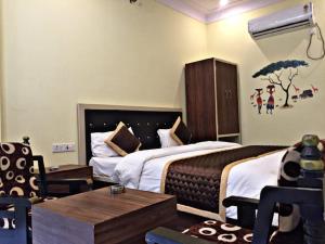 a hotel room with two beds and a table at The Comfort Home Stay Ranthambhore in Sawāi Mādhopur