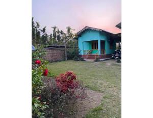 a blue house with a yard in front of it at Adoroni Guest House, Assam in Jyoti Gaon