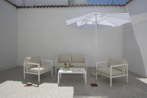 a room with three chairs and a table with an umbrella at Hostal Emeritae in Mérida