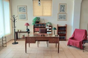 een woonkamer met een bureau en een roze stoel bij Villa Daphne in Tolo