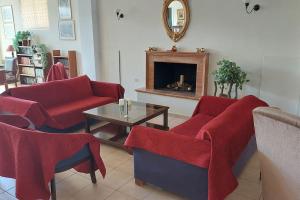 een woonkamer met rode meubels en een open haard bij Villa Daphne in Tolo