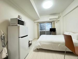 a bedroom with a bed and a microwave on top of a refrigerator at A&C STAY Shin-Osaka Higashikuchi 83 in Osaka