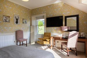 a hotel room with a desk and a bed and a television at The Bank House at Scotland's Hotel in Pitlochry