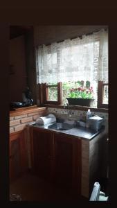 uma cozinha com um lavatório e uma janela em Chale Raio De Luz em Visconde de Mauá