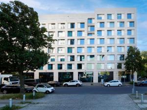 un bâtiment blanc avec des voitures garées devant lui dans l'établissement B&B Hotel Berlin-Tiergarten, à Berlin