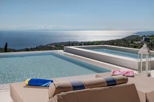a swimming pool with chairs and a view of the water at Archontiko Stoufi in Skinária