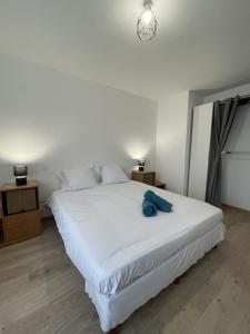 Un dormitorio con una cama blanca con una toalla azul. en Le Dalhia - Campagne - 6 pers - Rêve au Mans, en Noyen-sur-Sarthe