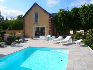 een zwembad met stoelen en een huis bij L'Ecolière - Villa Piscine Chauffée - Rêve au Mans in Teillé