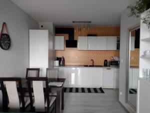 cocina con armarios blancos, mesa y sillas en Apartamenty Piastów, en Cracovia