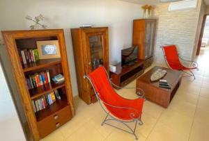 a living room with a red chair and a desk at Corralejo Beach Villa San Antonio- Private Heated Pool, Breathtaking Sea View, BBQ, Fast Wifi by Amazzzing Travel in Corralejo