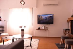 sala de estar con mesa y TV en la pared en Antonia's city apartment, en Ioannina