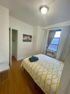 1 dormitorio con 1 cama con manta amarilla y blanca en Room in a 2 Bedrooms apt. 10 minutes to Time Square!, en West New York