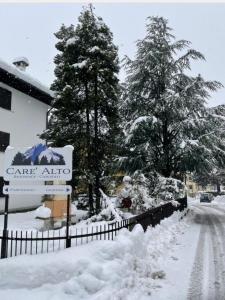 una strada innevata con alberi e una recinzione di Carè Alto a Carisolo