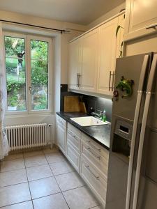 cocina con nevera y fregadero en La Maison Bleue à 2 pas du Lac du Neuchâtel, en Hauterive