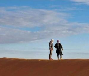 dos personas de pie en la cima de una duna de arena en Honeymoon Luxury Glamping en Hassilabied