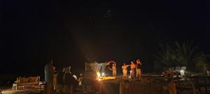 a group of people standing around a fire at night at Honeymoon Luxury Glamping in Adrouine