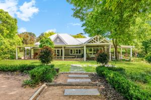 a house with a porch and a yard at Chanticleer Gardens Barn cottage with a Pool in Dural