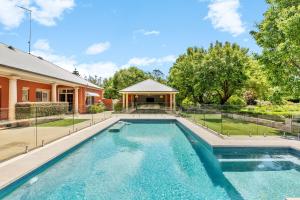 a swimming pool in front of a house at Chanticleer Gardens Barn cottage with a Pool in Dural