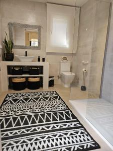 ein Badezimmer mit einem Waschbecken, einem WC und einem Teppich in der Unterkunft Anubha House in Peralejo