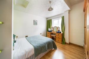 a bedroom with a bed and a dresser and a window at Livestay-Affordable 2-Bed House in Luton in Luton