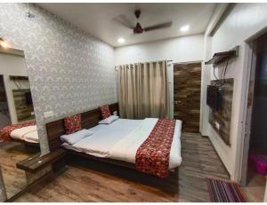 a bedroom with a bed and a tv in it at Geeta Lodge, Solapur in Solapur