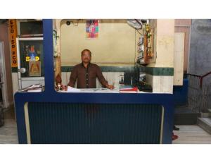 Un uomo in piedi dietro un bancone in una cucina di Geeta Lodge, Solapur a Solapur
