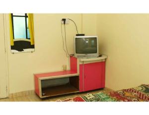 una TV seduta su un mobile rosso in una stanza di Geeta Lodge, Solapur a Solapur