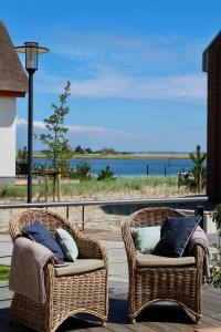 two wicker chairs on a deck with a view of the ocean at Ostsee - Reetdachhaus Nr 44 "Reethüs - Marina" im Strand Resort in Heiligenhafen