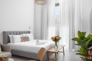 a bedroom with a bed and a table with a vase of flowers at דירת גן מפנקת בסיסייד 100 מטר מהים - By Edomlux in Eilat