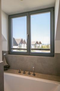 2 ventanas sobre una bañera en el baño en Ostsee - Reetdachhaus Nr 44 "Reethüs - Marina" im Strand Resort, en Heiligenhafen
