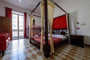 ナポリにあるNapoli Centrale di Fabio e Veronica LTのベッドルーム1室(赤いカーテン付きの天蓋付きベッド1台付)