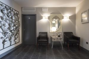 a hallway with two chairs and a table and a mirror at Hostal Emeritae in Mérida