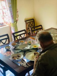 um homem sentado numa mesa com pratos de comida em Sunflower Inn em Dambulla