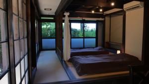 2 camas en una habitación con 2 ventanas en Antique Villa Lotus（古民家ロータス）, en Tsukuba