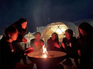 a group of people standing around a table with a fire at Glamping&Port結 in Shimada