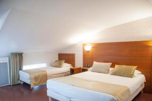 una habitación de hotel con 2 camas en una habitación en The Originals City, Hôtel Bristol, Le Puy-en-Velay en Le Puy-en-Velay