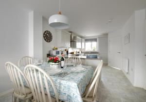 a dining room with a table and chairs with a table and a kitchen at The Salty Dog in Aldeburgh