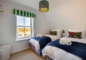 two beds in a room with a window at The Salty Dog in Aldeburgh