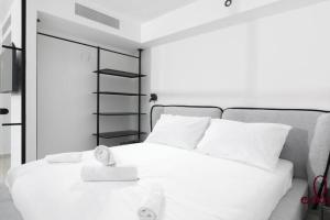 a bedroom with a white bed with a clock on it at דירת חדר שינה וסלון 50 מטר מהים - By Edomlux in Eilat