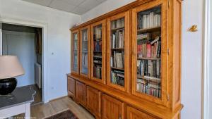 a large wooden cabinet with books in it at La Closerie des Anges in Saulx-de-Vesoul