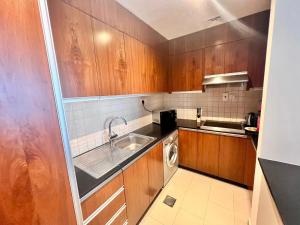 a small kitchen with wooden cabinets and a sink at Spirit Tower - 1BR Apartment - Allsopp&Allsopp in Dubai