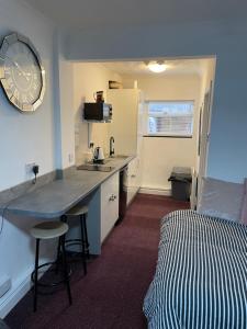 a room with a kitchen and a bed and a clock at Apartments Azalea Terrace in Sunderland