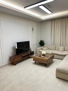 sala de estar con sofá y TV de pantalla plana en شقة في حي الروضة الراقي en Yeda