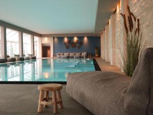 - un salon avec une piscine, un canapé et une chaise dans l'établissement Grand Hotel Seeschlösschen Sea Retreat & SPA, à Timmendorfer Strand