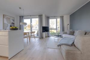 Strandglück في تيميندورفير ستراند: غرفة معيشة بيضاء مع أريكة وطاولة