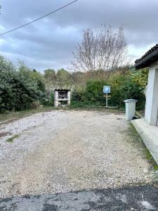 a gravel parking lot with a gate and a sign at La maisonnette in Montauban