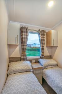 two beds in a small room with a window at Luxury 8 Berth-Wheelchair Access in Port Seton