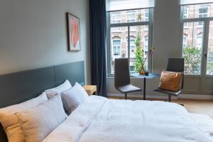 a bedroom with a bed and two chairs and a table at Vondel 99 in Amsterdam