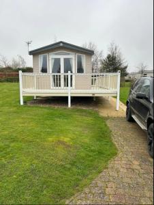 a house with a porch and a car parked in a yard at Luxury 8 Berth-Wheelchair Access in Port Seton