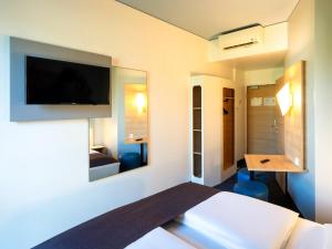 ブラウンシュヴァイクにあるB&B Hotel Braunschweig-Cityのベッド1台、壁掛けテレビが備わるホテルルームです。